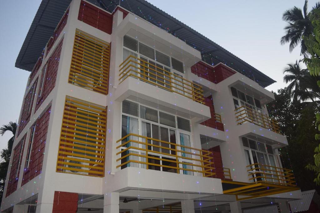 een wit en rood gebouw met gele ramen bij Oasis Resort in Diveagar
