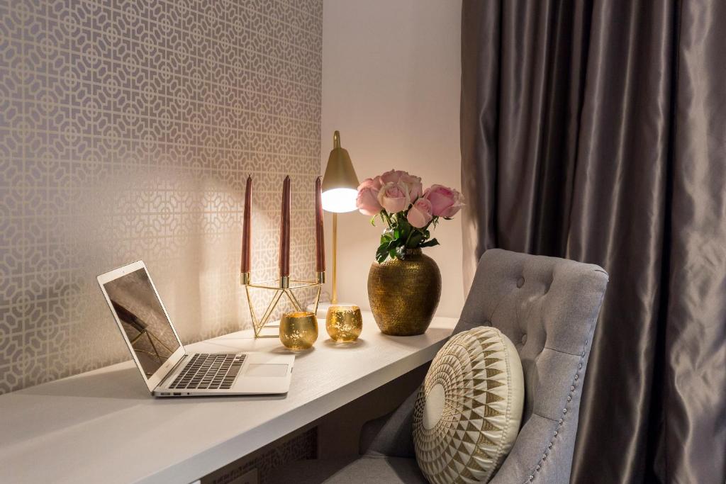 a desk with a laptop and a chair and a vase with flowers at MM House in Zagreb