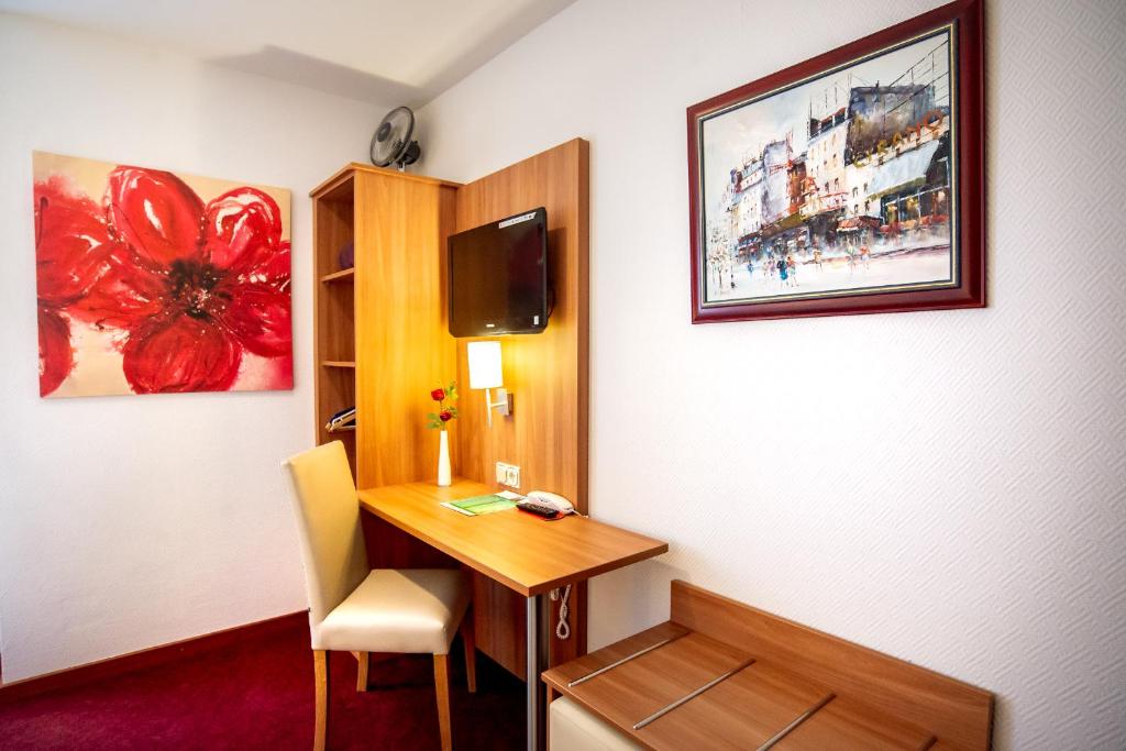 a hotel room with a desk and a tv at Hotel Domblick Garni in Cologne