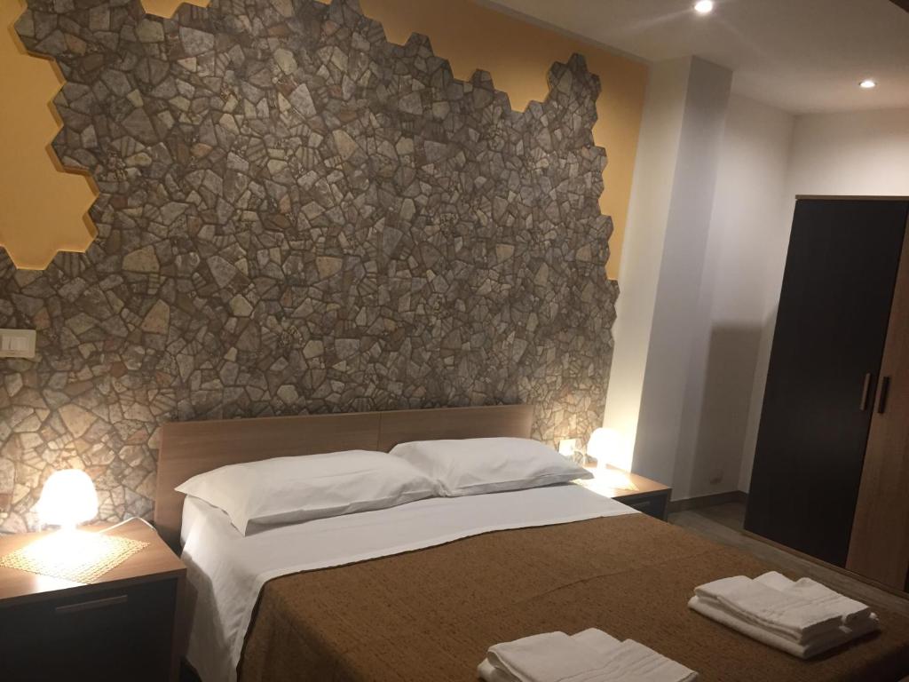 a bedroom with a bed with a stone wall at Etna Blick View in Zafferana Etnea