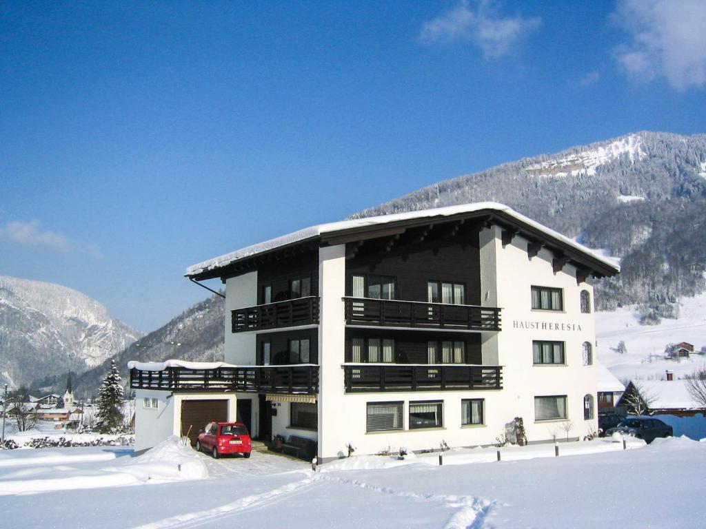 a building with a red car parked in the snow at Haus Theresia in Mellau