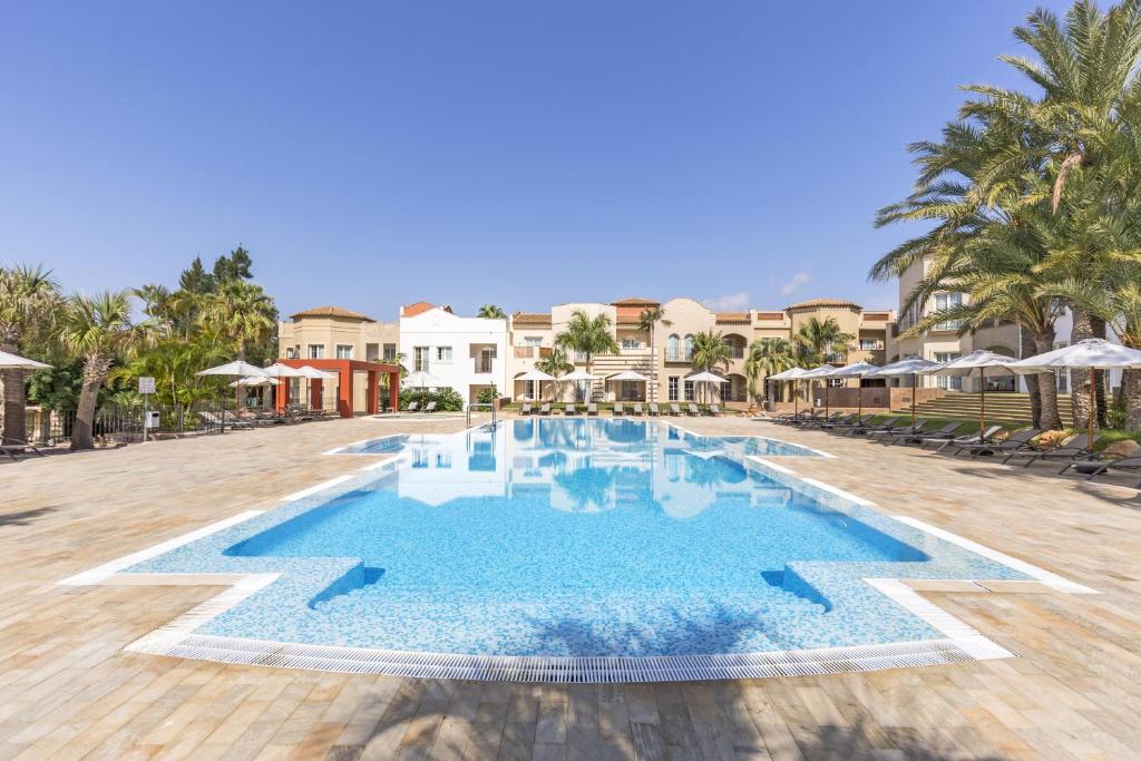 a pool at a resort with palm trees and umbrellas at LA SELLA PREMIUM lifestyle Apartments in Denia