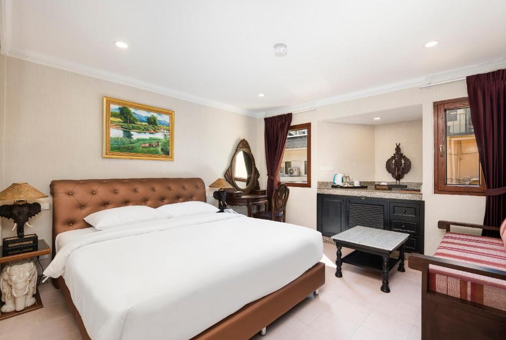 a bedroom with a large white bed and a desk at The Ambiance Hotel in Pattaya Central