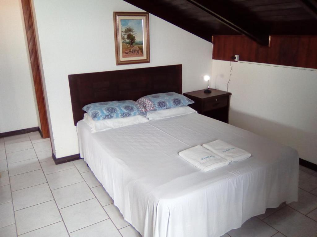 a bedroom with a large white bed with blue pillows at Lola Apart in Bombinhas