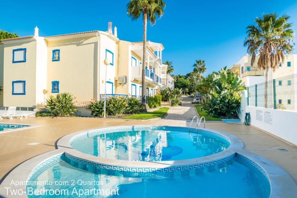 a swimming pool in front of a building with palm trees at Akisol Albufeira Ocean II in Albufeira