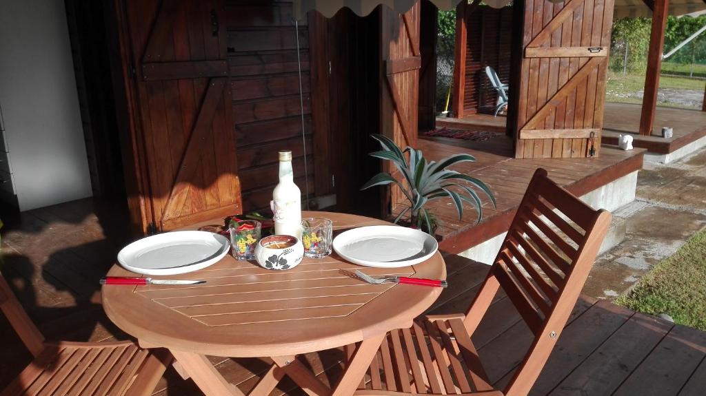 a wooden table with plates and a bottle on a patio at le "BWA ' KAO" in Capesterre-Belle-Eau