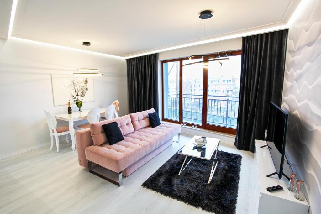 salon z różową kanapą i stołem w obiekcie Apartament z basenem i widokiem na Motławę w Gdańsku