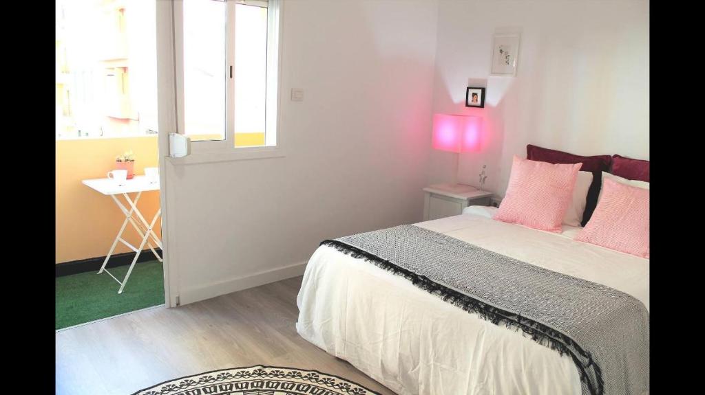 Un dormitorio con una cama con almohadas rosas y una ventana en Santa Cruz Rambla, en Santa Cruz de Tenerife