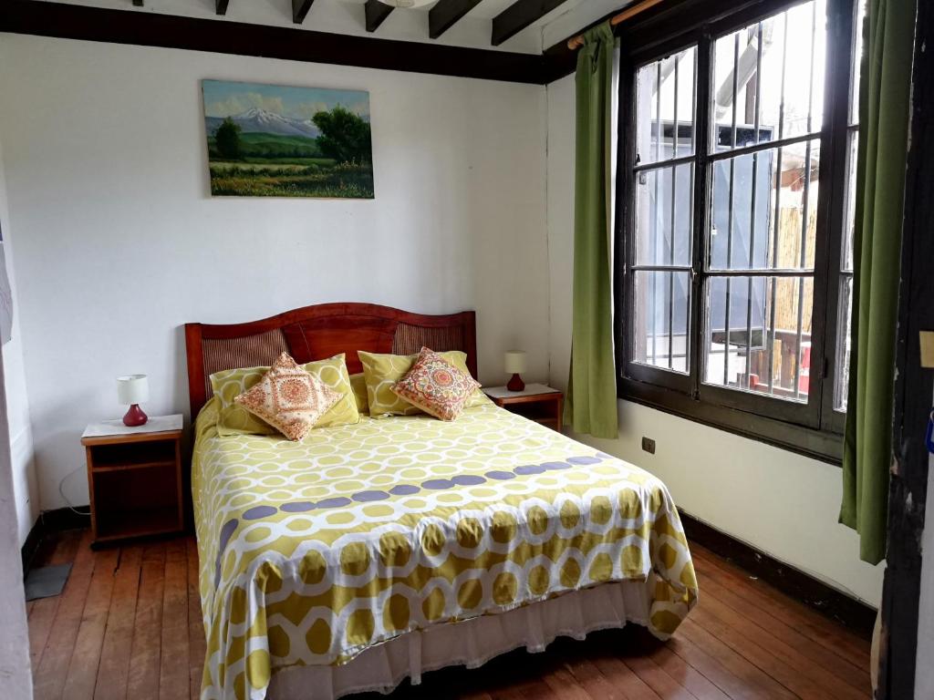 1 dormitorio con 1 cama con edredón amarillo y blanco en Hostal Casona de Chorrillos, en Viña del Mar