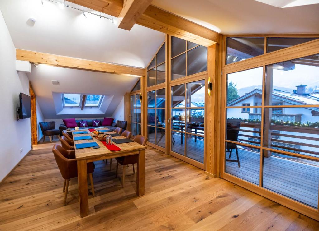 uma sala de jantar com mesa, cadeiras e janelas de vidro em Gapartments em Garmisch-Partenkirchen