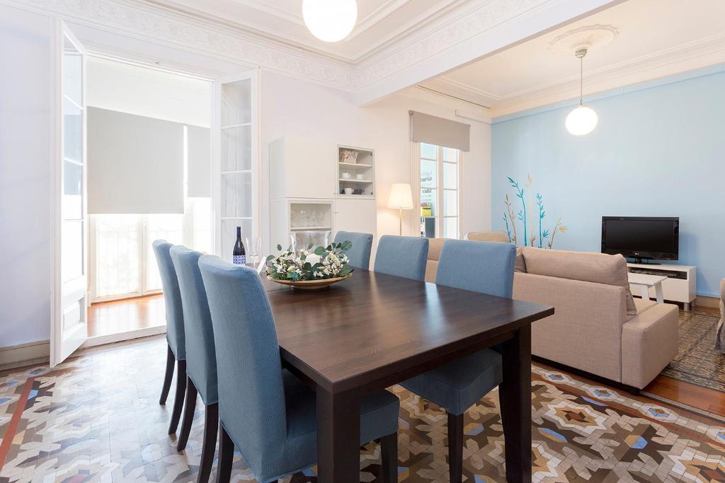 a dining room with a wooden table and blue chairs at Luxury y Elegant Apartment in the centre in Barcelona