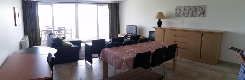 een woonkamer met een tafel en stoelen en een raam bij Infinity I, 0405 in Oostende