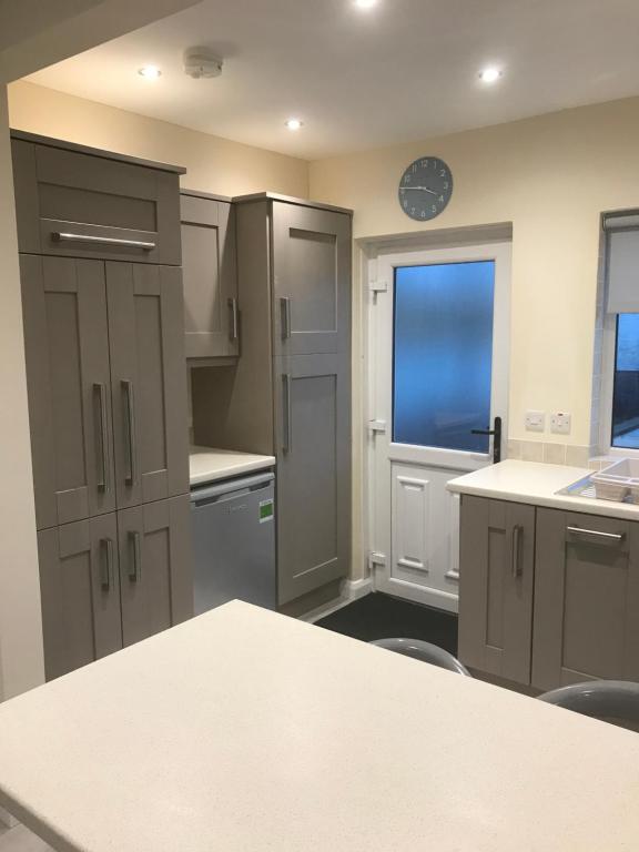 a kitchen with gray cabinets and a clock on the wall at 8 Queenora Avenue in Portstewart