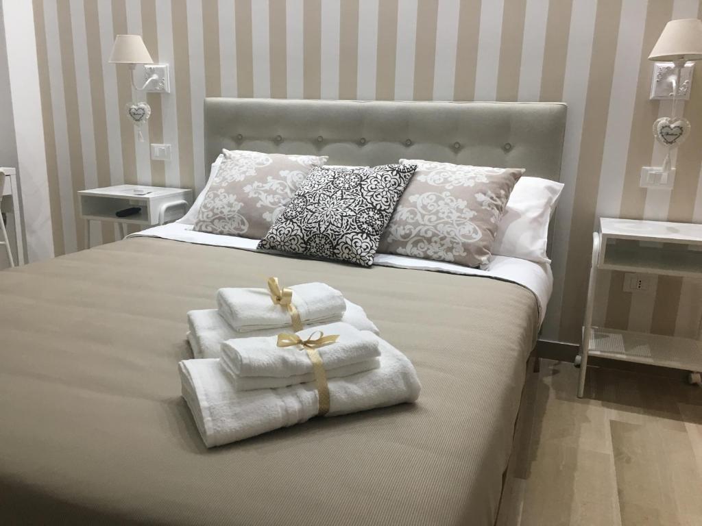 una camera da letto con un letto con asciugamani e cuscini di Donna Laudonia ad Altamura