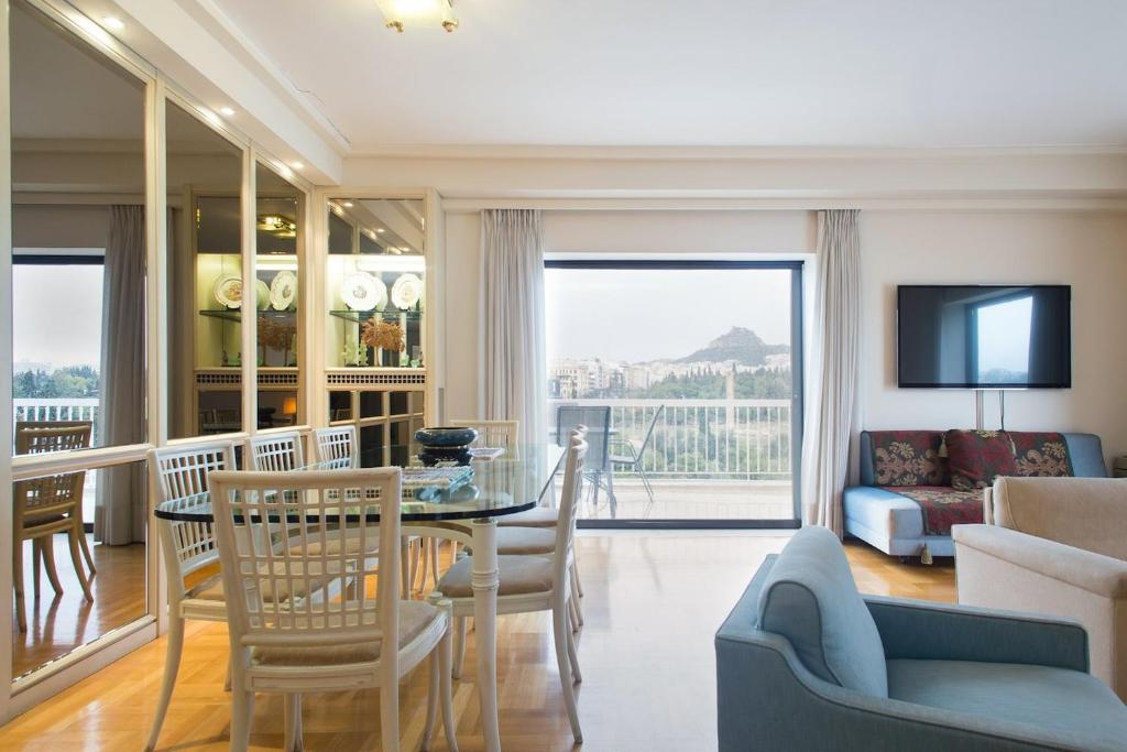 een woonkamer met een tafel en stoelen en een bank bij Alexander's Penthouse in Athene