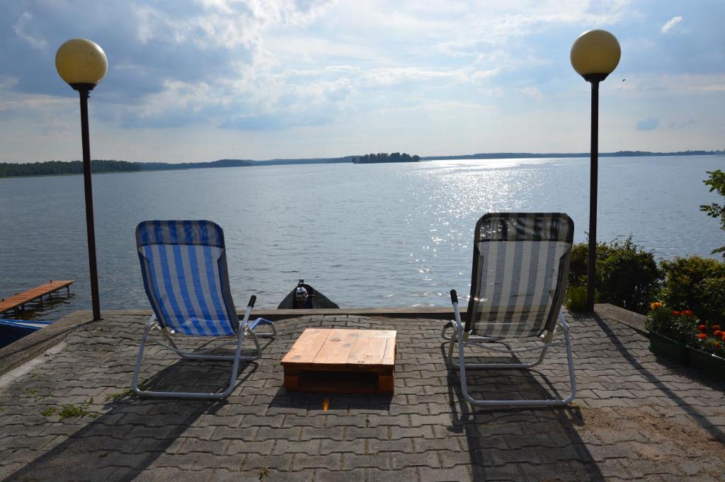 ギジツコにあるMazurska Kwatera-Rezerwat Fuledzki Rógの湖上の椅子2脚と木製テーブル