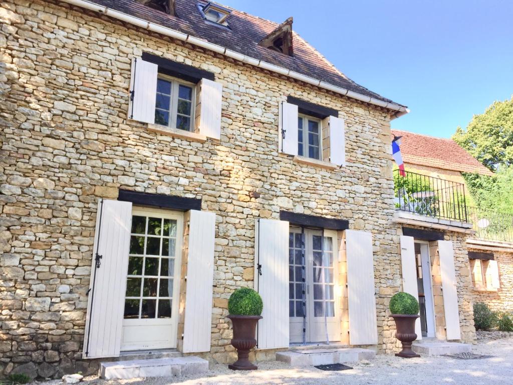 Casa de piedra con puertas y ventanas blancas en Gîte Le Recoux, en Mouzens