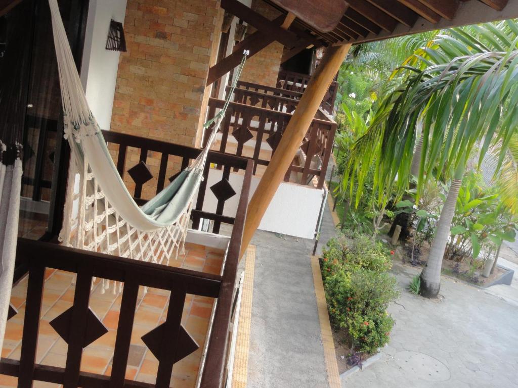 a porch with a hammock and some palm trees at Apartamentos La Piazzetta Duplex in Pipa