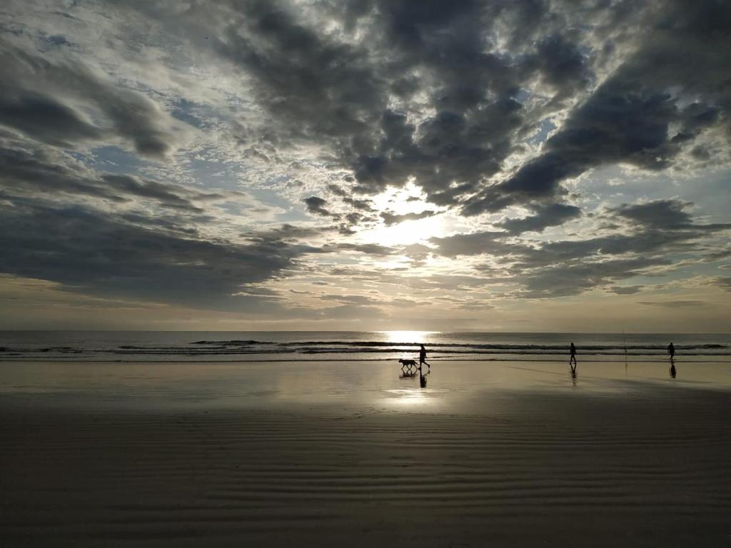 2 personnes debout sur une plage au coucher du soleil dans l'établissement Acomodação Ruth Guaratuba, à Guaratuba