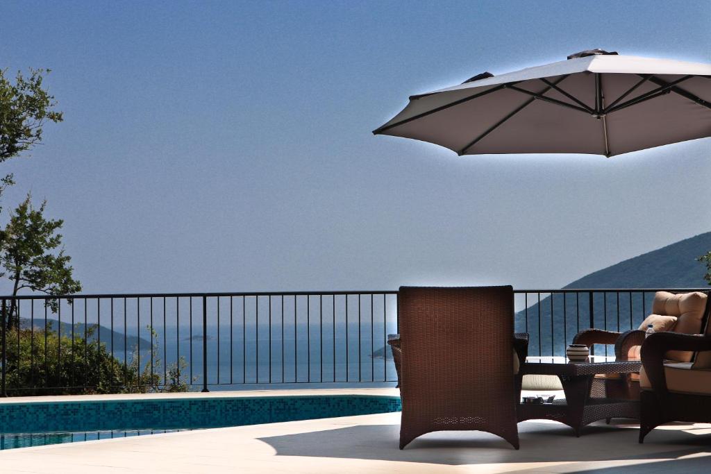 eine Terrasse mit einem Sonnenschirm und Stühlen neben einem Pool in der Unterkunft Villa Sladovic in Herceg-Novi