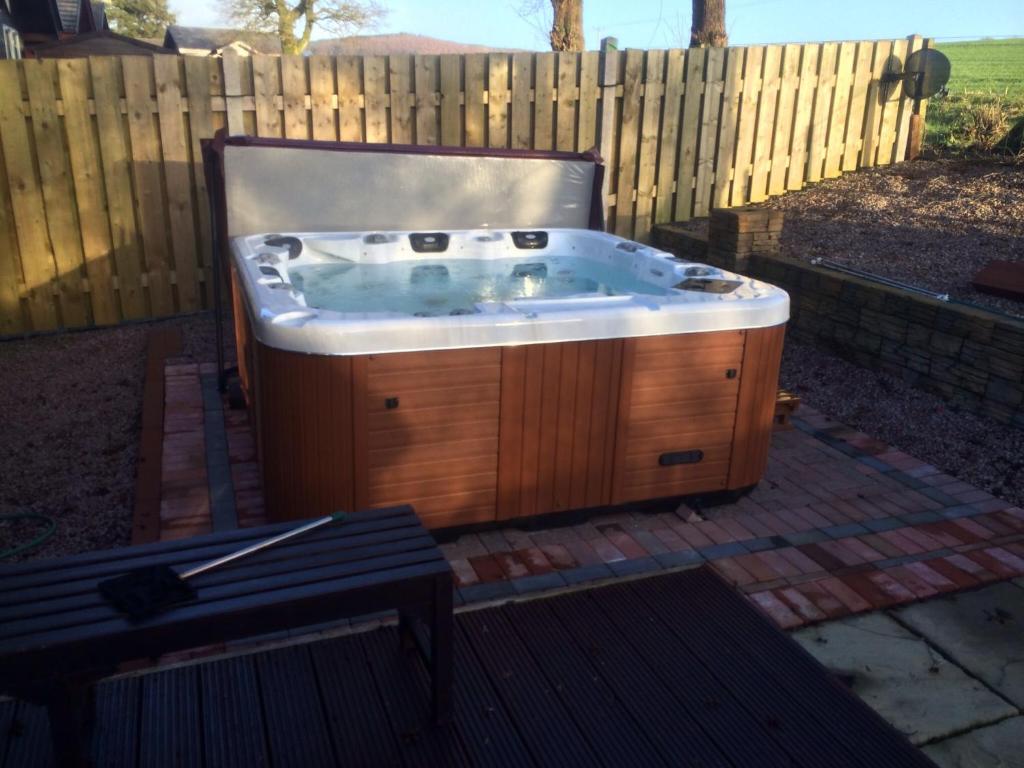 a jacuzzi tub in front of a wooden fence at Woodburn Lodge in Dumfries