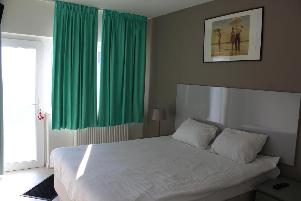 Schlafzimmer mit einem großen weißen Bett und grünen Vorhängen in der Unterkunft Logie Rotem in Dilsen-Stokkem