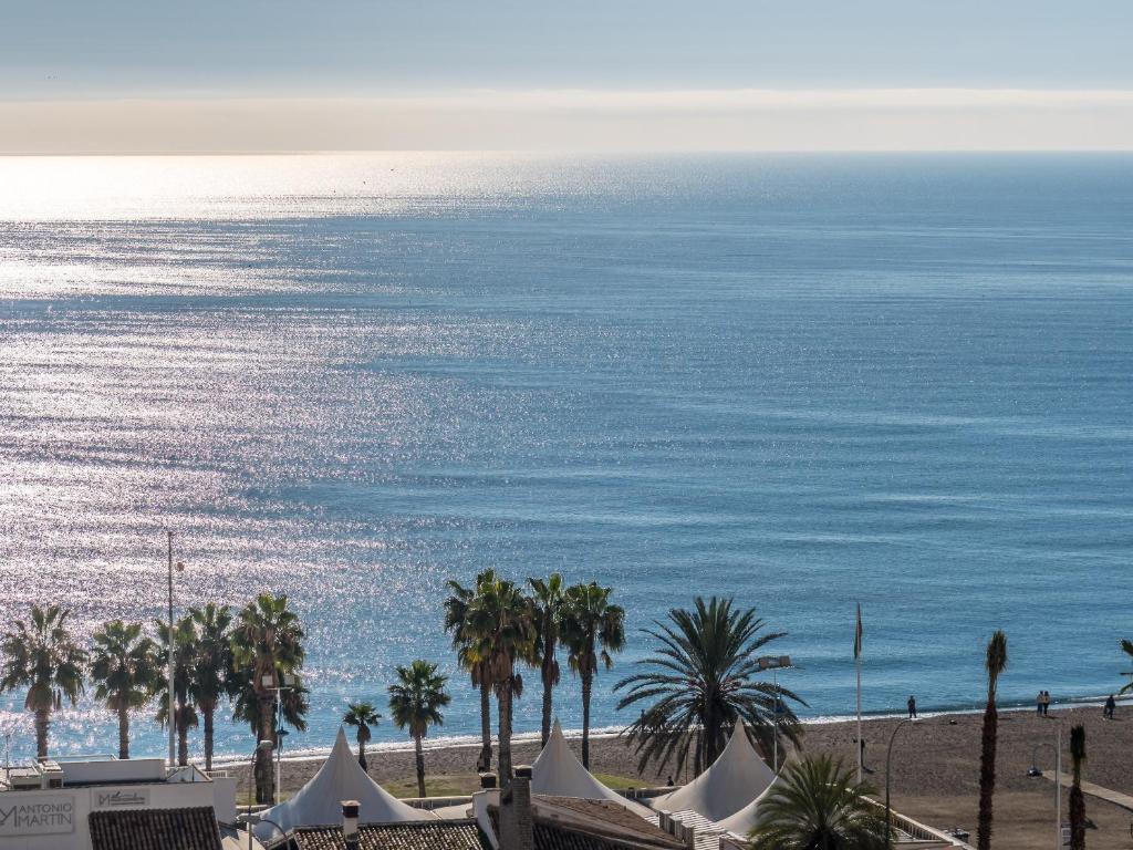 - une vue sur la plage bordée de palmiers et l'océan dans l'établissement MALAGUETA SEA VIEW - PREMIUM APARTMENT, à Malaga