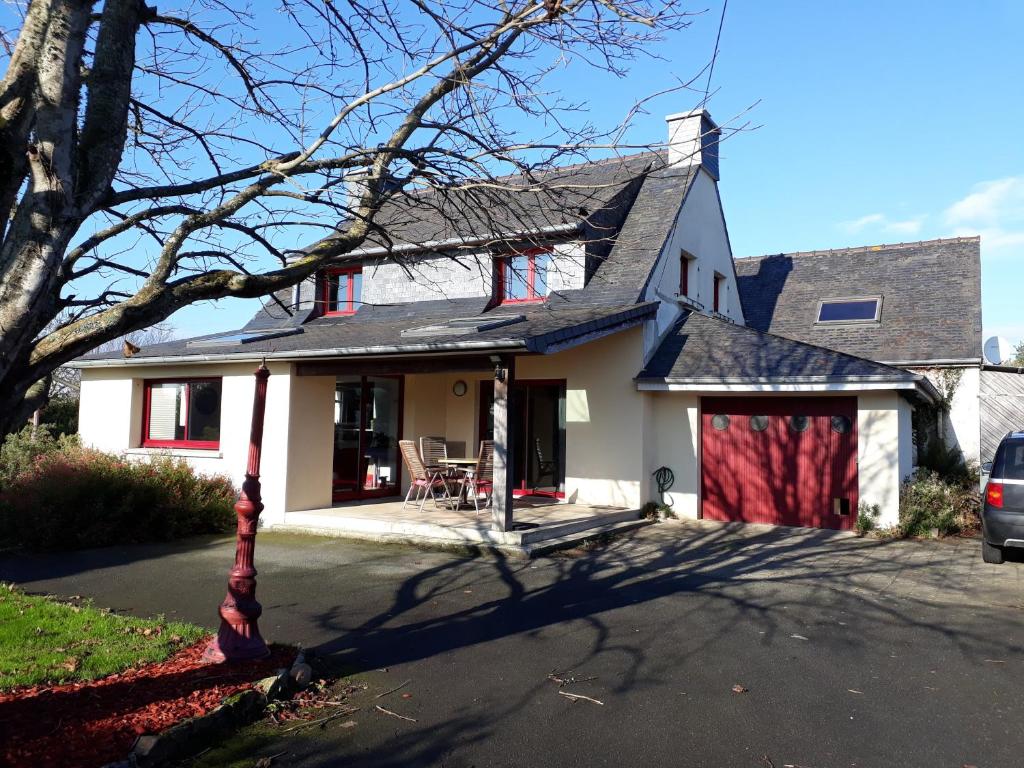 une maison blanche avec un garage rouge dans l'établissement La maison de Keralies, à Pleumeur-Bodou