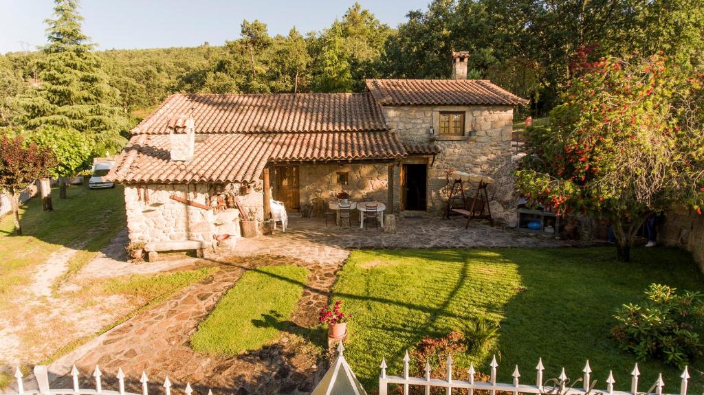 una vieja casa de piedra con una valla blanca delante de ella en Quinta Vale da Ginjeira, en Quinta da Carrapata