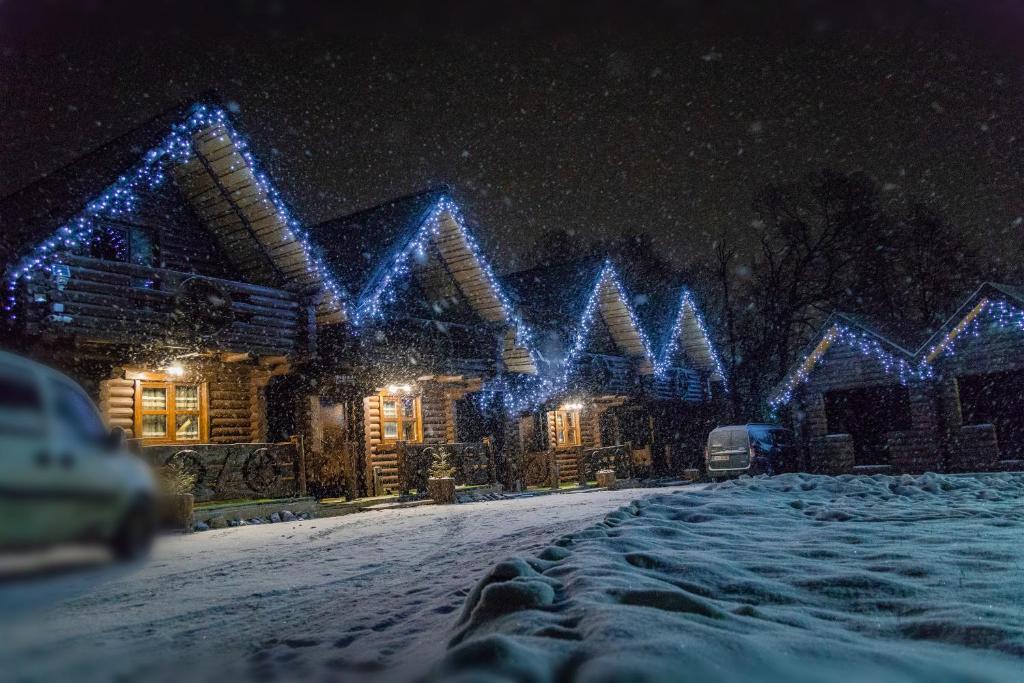 a house covered in christmas lights in the snow at Cottage Hata Zustrich in Bukovel