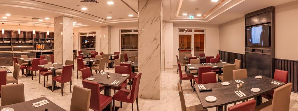 un ristorante con tavoli in legno e sedie rosse di Cerviola Hotel a Marsaskala