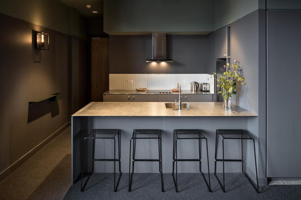 a kitchen with a counter with three bar stools at The Chamberson in Dunedin