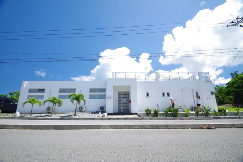 biały budynek z palmami przed nim w obiekcie ＵｍｉＯｔｏ ウミオト 女子旅に大人気のゲストハウス w mieście Miyako-jima