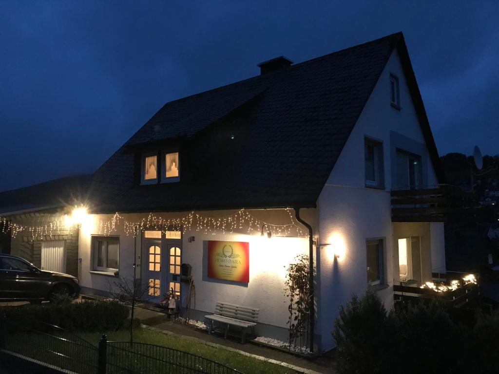 une maison blanche avec des lumières de Noël allumées la nuit dans l'établissement Sonnenhaus Bara, à Winterberg