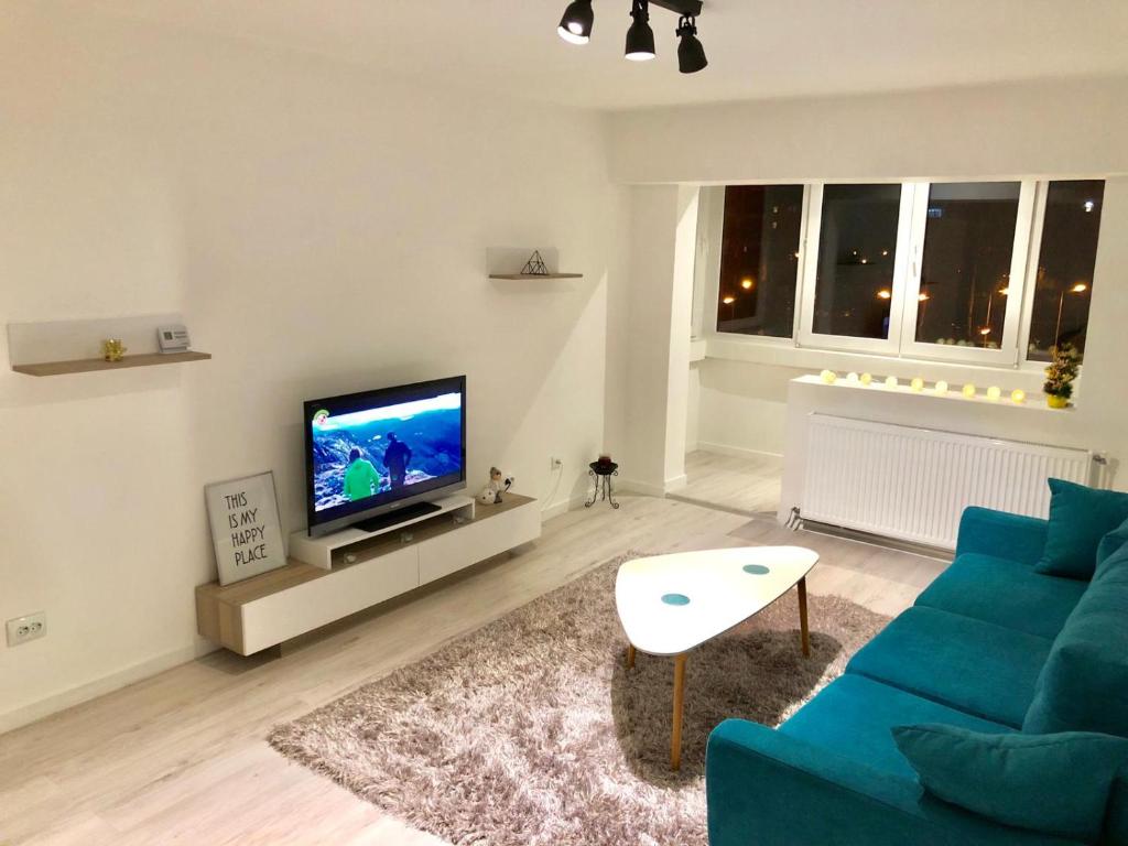 uma sala de estar com um sofá azul e uma televisão em Mountain Residence em Brasov