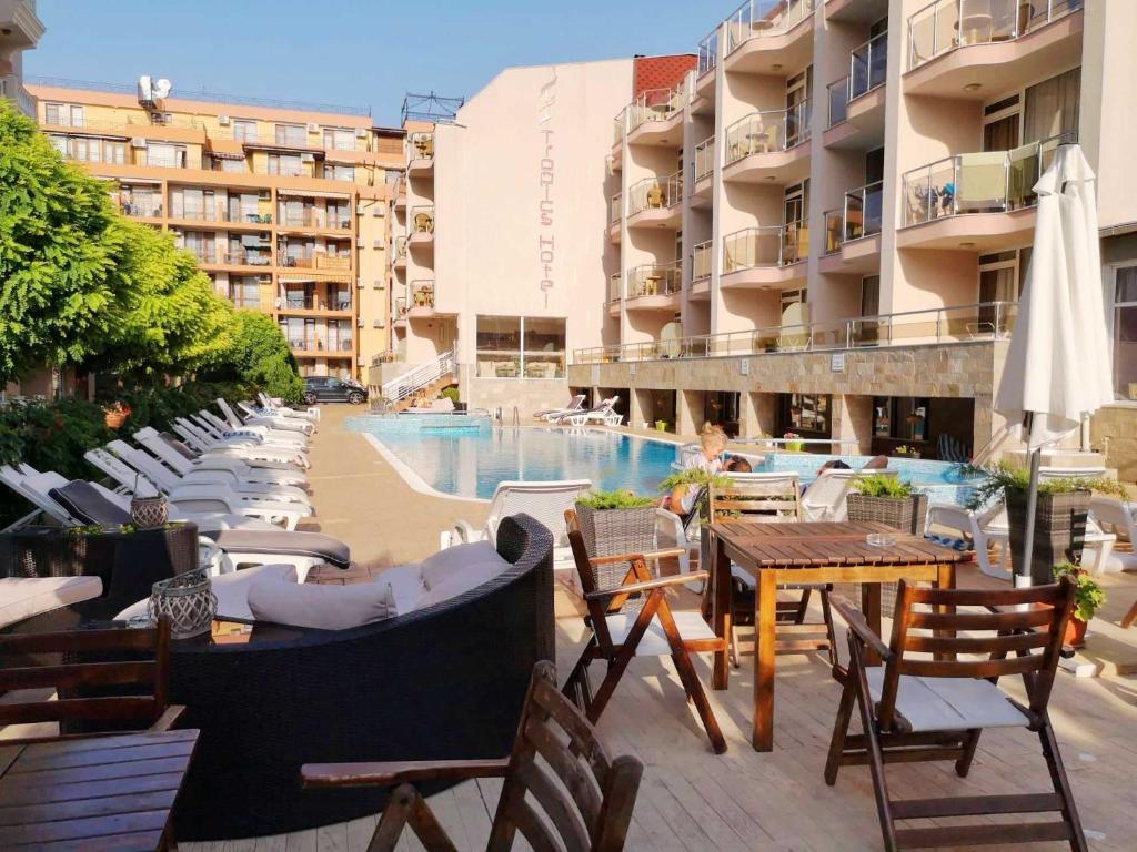 un patio del hotel con piscina, mesas y sillas en Tropics Hotel - Ultra All Inclusive, en Sveti Vlas