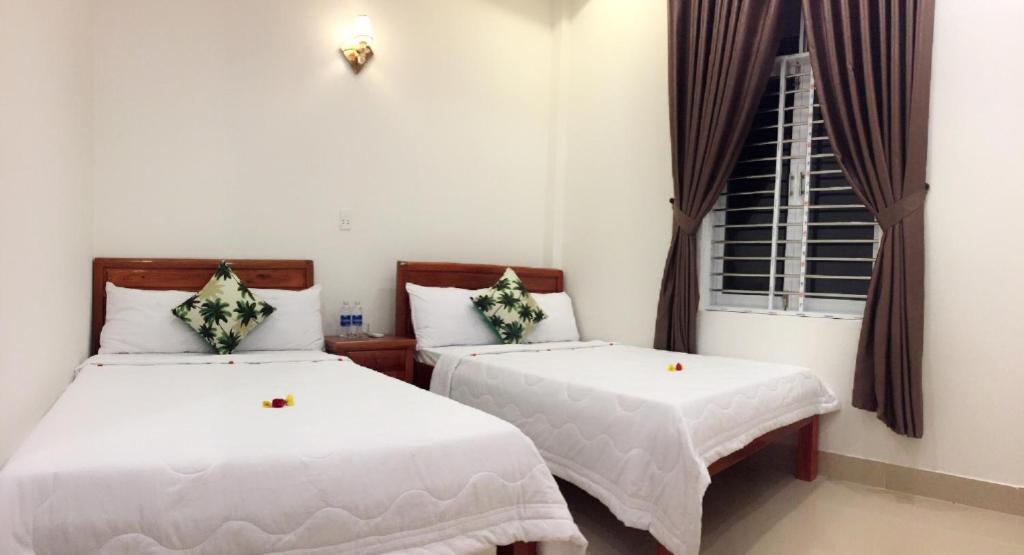 two beds in a room with a window at CANH DUONG MOTEL in Lang Co