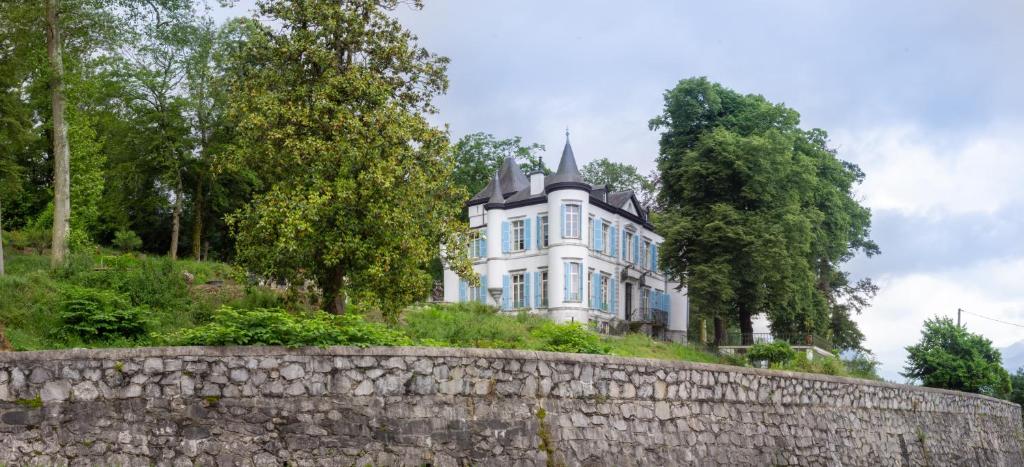 ein großes weißes Haus auf einem Hügel mit einer Steinmauer in der Unterkunft Château de Druon in Sévignacq-Meyracq