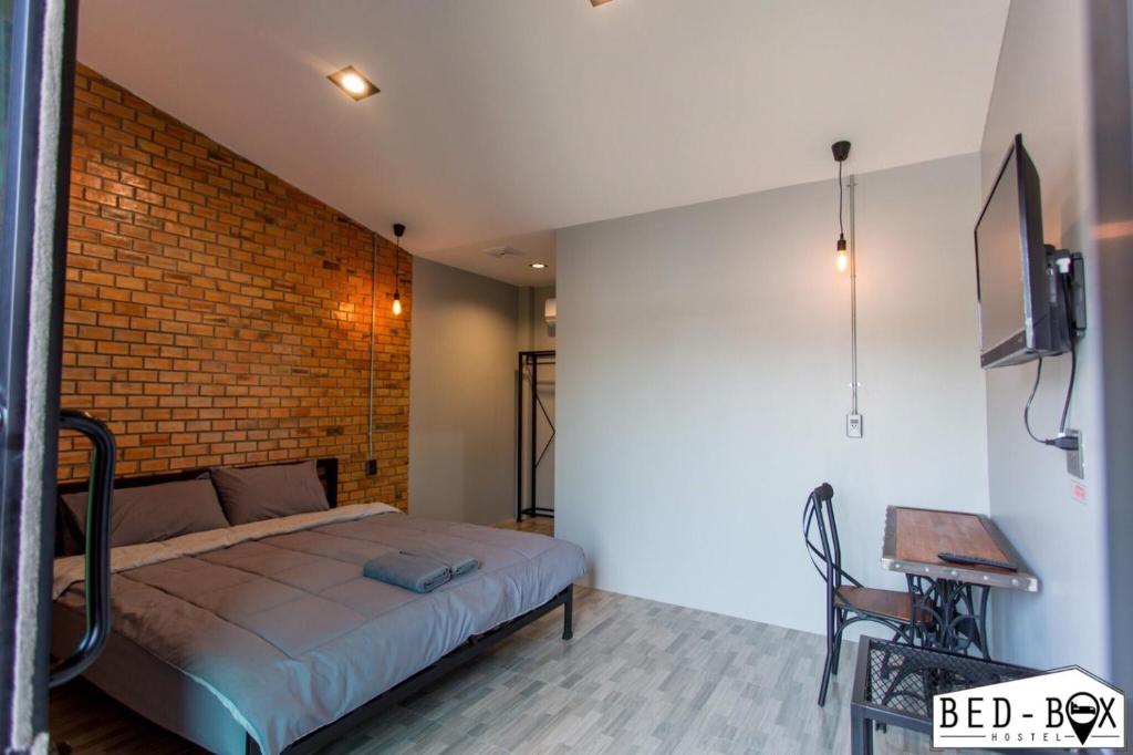 a bedroom with a bed and a brick wall at Bed Box in Nakhon Ratchasima
