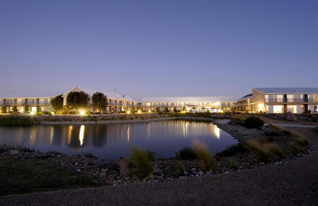a hotel at night with a pond in the foreground at Quest Williamstown North in Williamstown