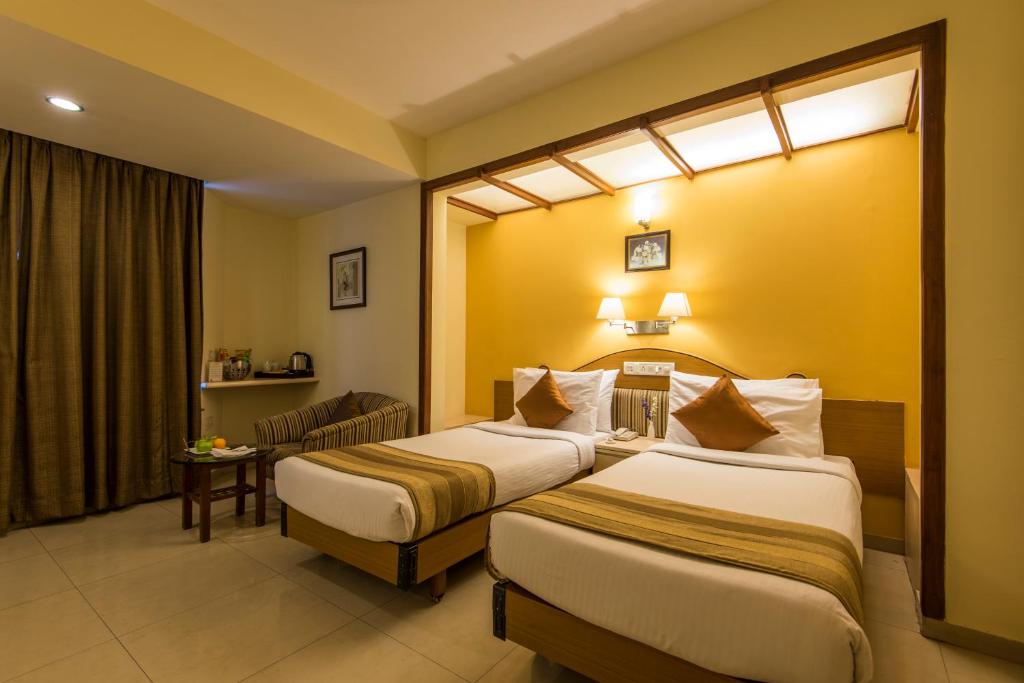 a hotel room with two beds and a window at Hotel Park Central Comfort- E- Suites in Pune
