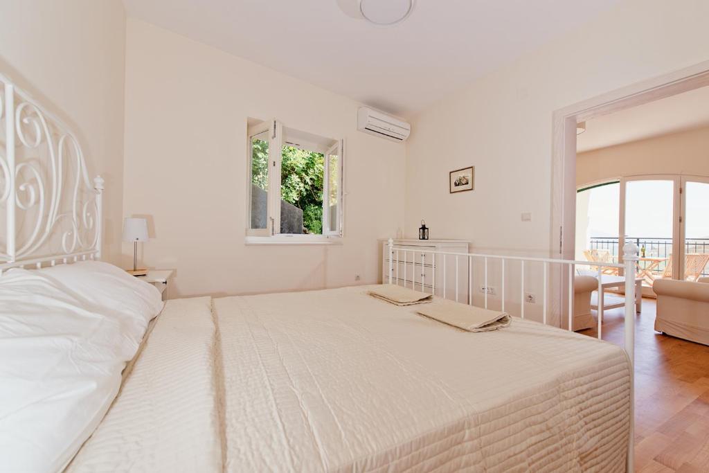 een witte slaapkamer met een groot bed en een raam bij Apartment Olivia in Herceg-Novi