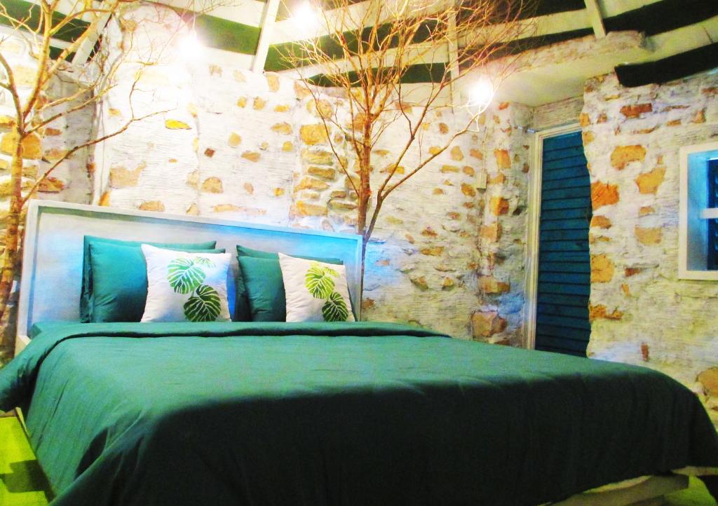 a bedroom with a bed with a green comforter at Phu Nam House - Resort in Phú Quốc