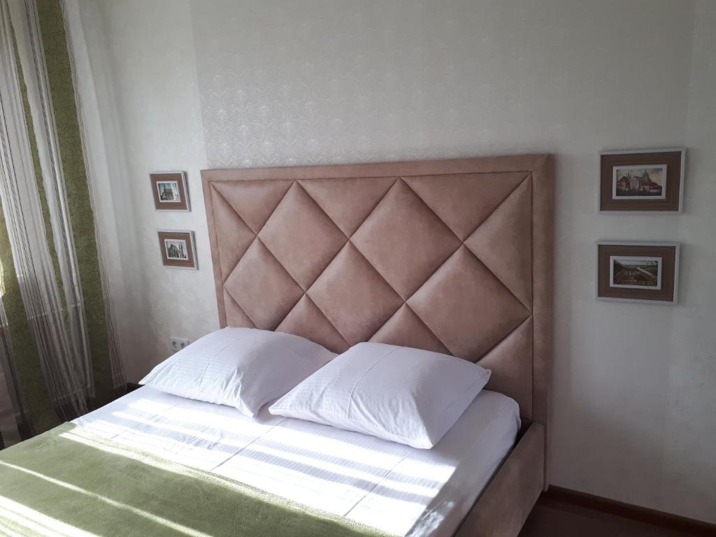 - un lit avec des oreillers blancs et une tête de lit marron dans l'établissement Nebesnoyi Sotni, à Jytomyr