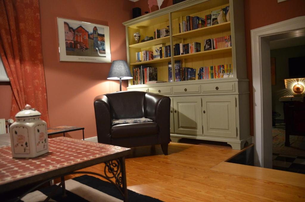ein Wohnzimmer mit einem Stuhl und einem Bücherregal in der Unterkunft Bickbargen - Haus mit 4 Schlafzimmern und Platz in Halstenbek