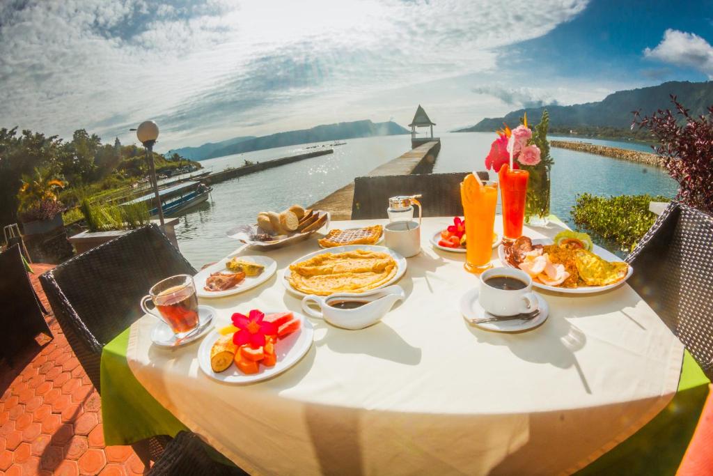 a table with food on it with a view of the water at Toba Village Inn in Tuk Tuk
