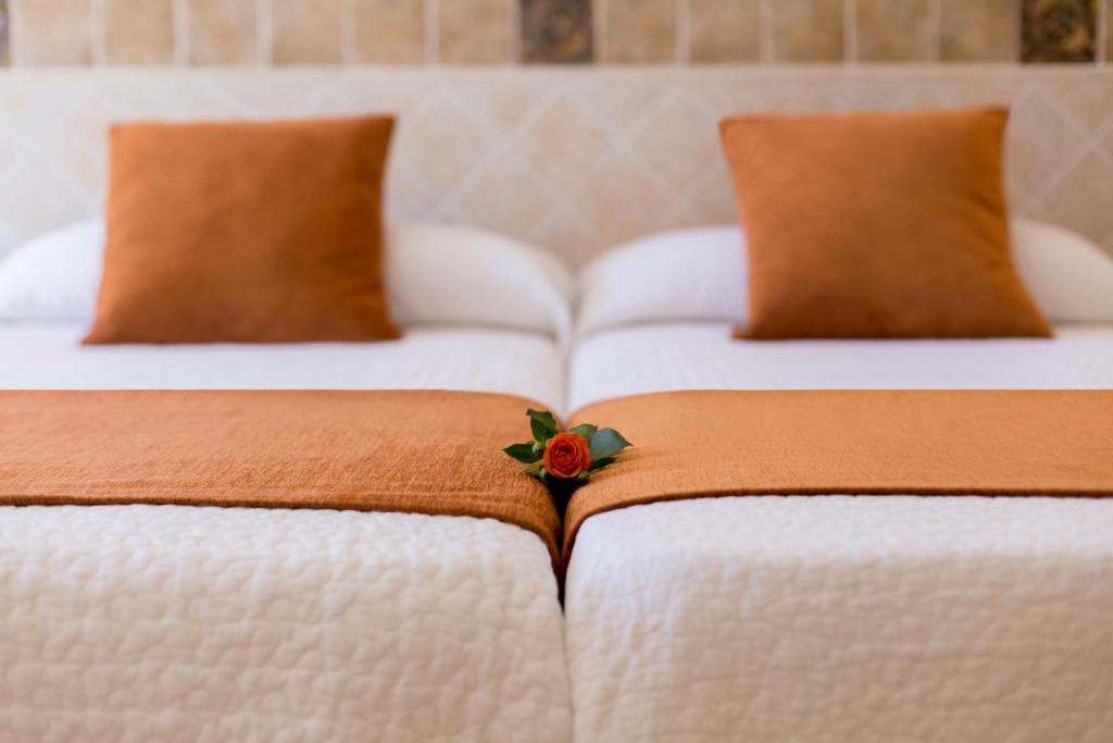 two white beds with a flower on the blanket at Hotel Plaza Cavana in Nerja