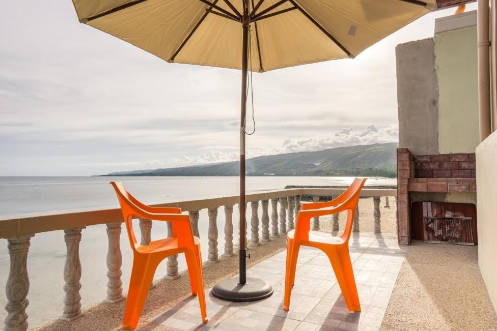 zwei orangefarbene Stühle und ein Regenschirm auf dem Balkon in der Unterkunft Kellocks' Seaview Apartelle in Dalaguete