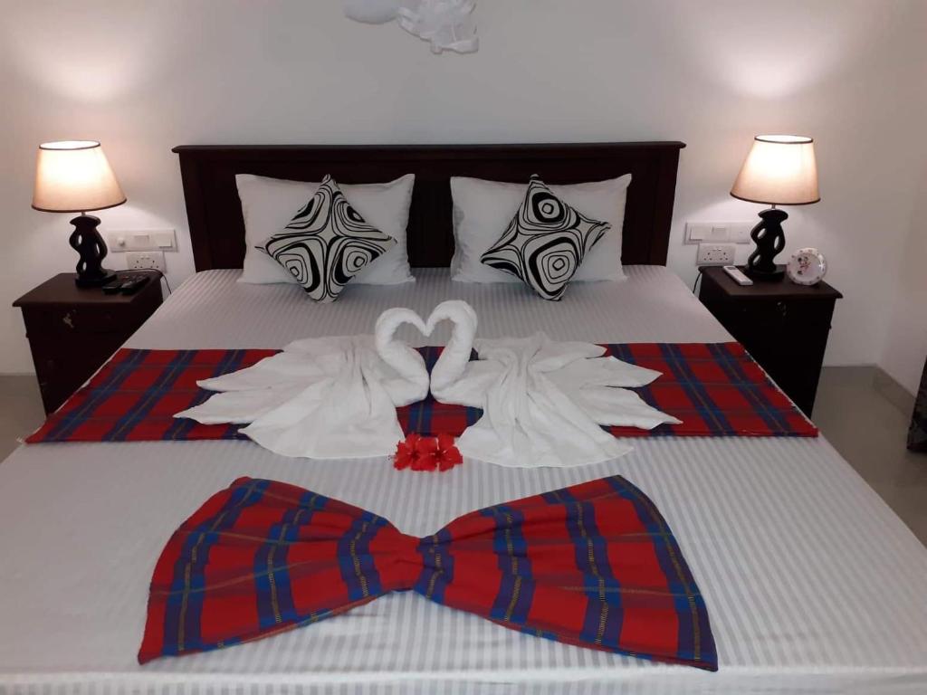 a bed with two shirts and a bow tie on it at Sigiri Hibiscus Villa in Sigiriya