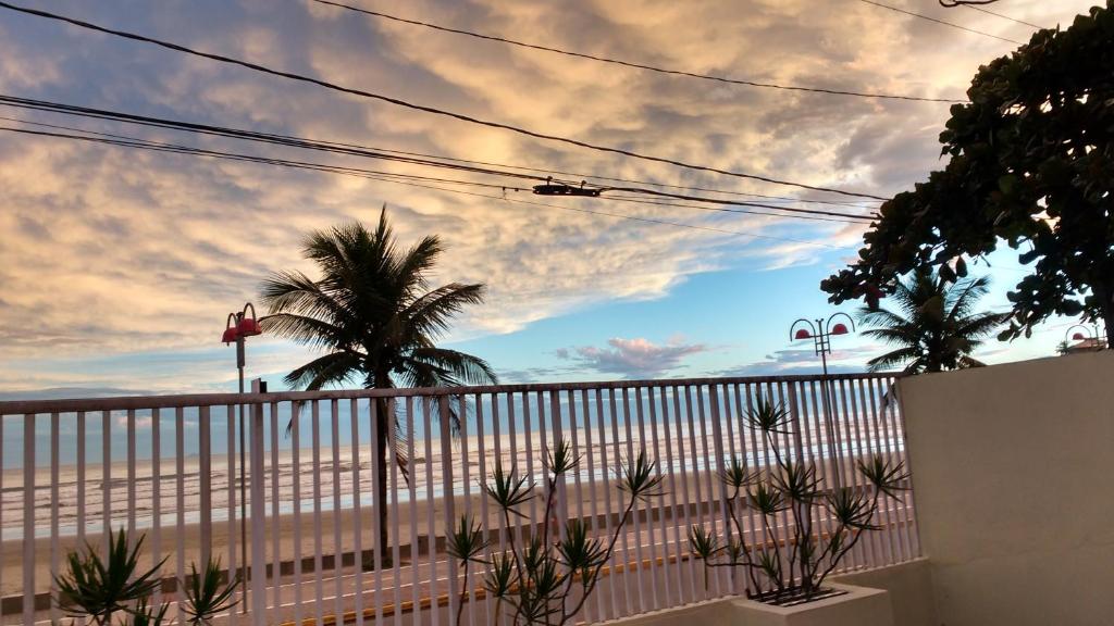 a view of the beach from a fence with palm trees at Pousada/Flat Praia Do Sonho in Itanhaém